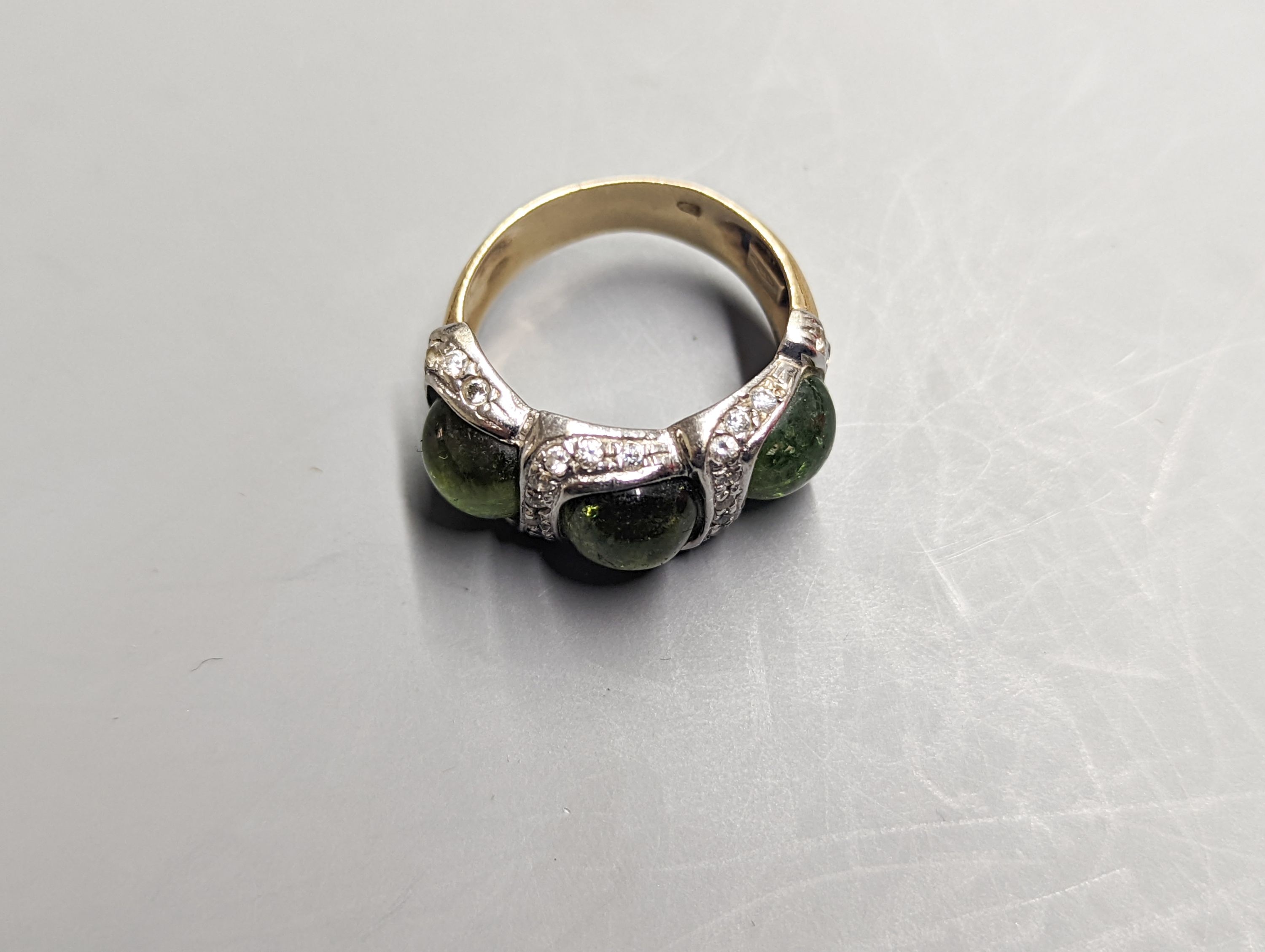 A modern 585 yellow metal, three stone green cabochon and diamond chip set dress ring, size N/O, gross weight 8.3 grams.
